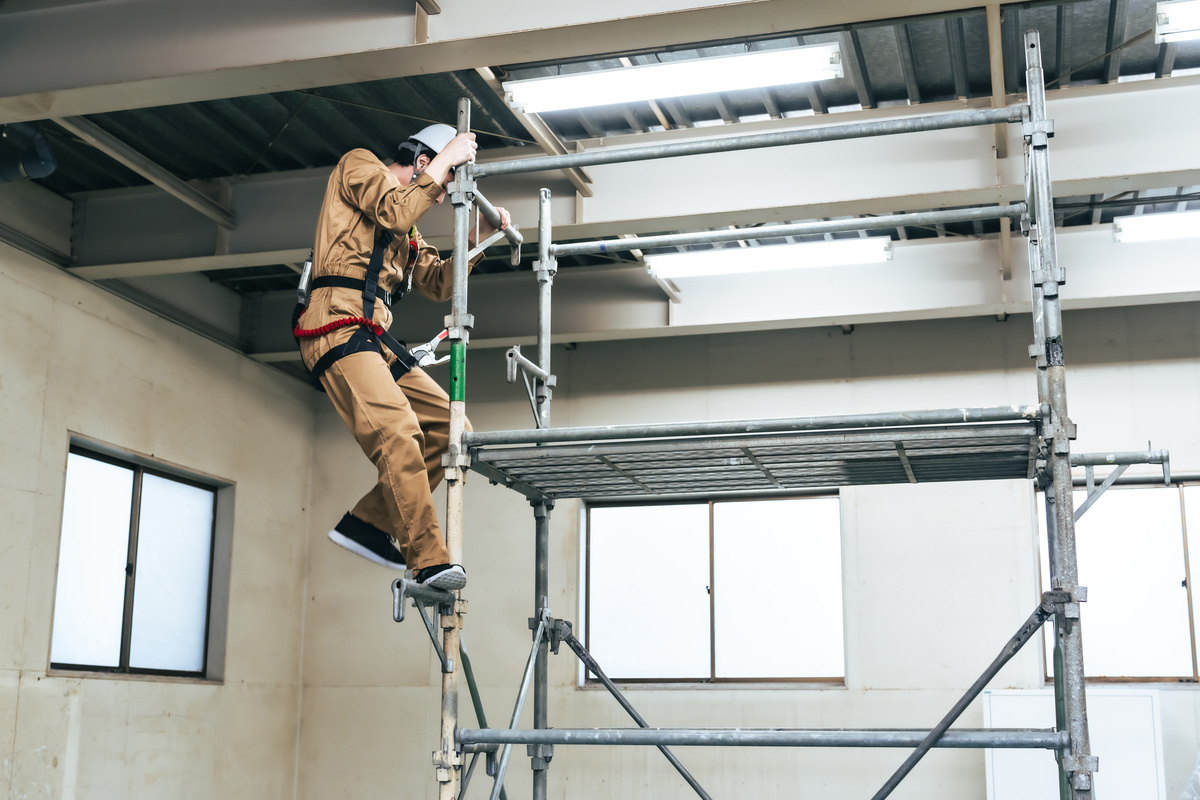 フルハーネスを着用して足場を登る作業員