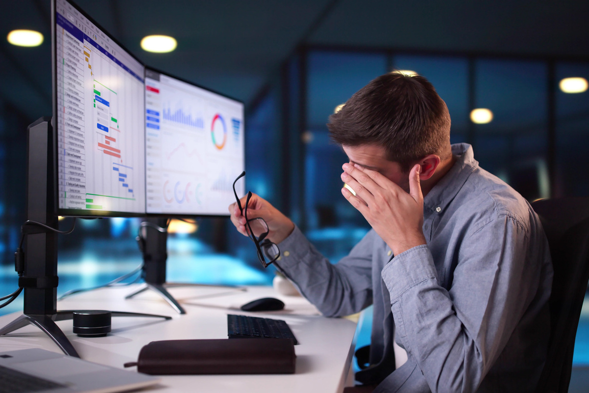 モニターの前で目をこする男性